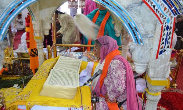 Description: A woman reads 'Guru Granth Sahib', the holy book of the Sikh religion.