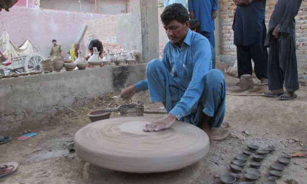 Description: A potter in the initial phase of making a pot. — Photo by Hanif Samoon