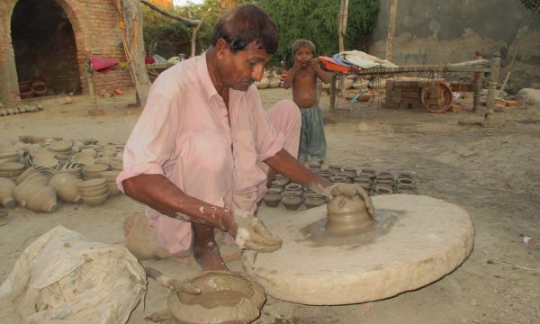 Description: A local potter in the initial stages of moulding a pot. — Photo by Hanif Samoon