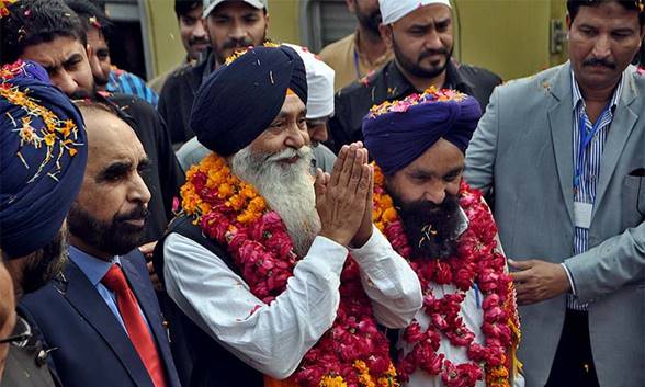 Description: Sikh devotees return the welcome gesture on their arrival at Wagah border. — APP