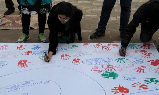 Description: Description: A member of the EFC Indian delegation writes a message of peace while on a visit to the Sanjan Nagar Public Education Trust in Lahore. — The Citizens Archive of Pakistan.