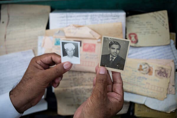 Description: Mr. Anwar holding photos of his father, Muhammad Anwar, left, and his friend Mr. Duggal.